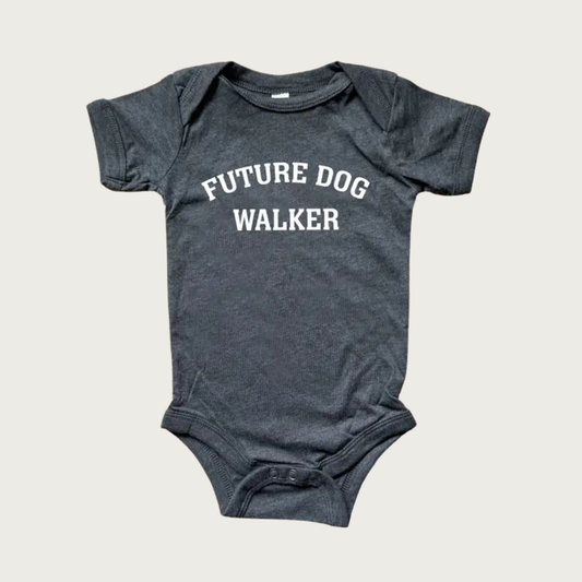 A dark heather gray baby onesie with 'FUTURE DOG WALKER' printed in white, all caps arched text across the chest. Two snap closure on the bottom.