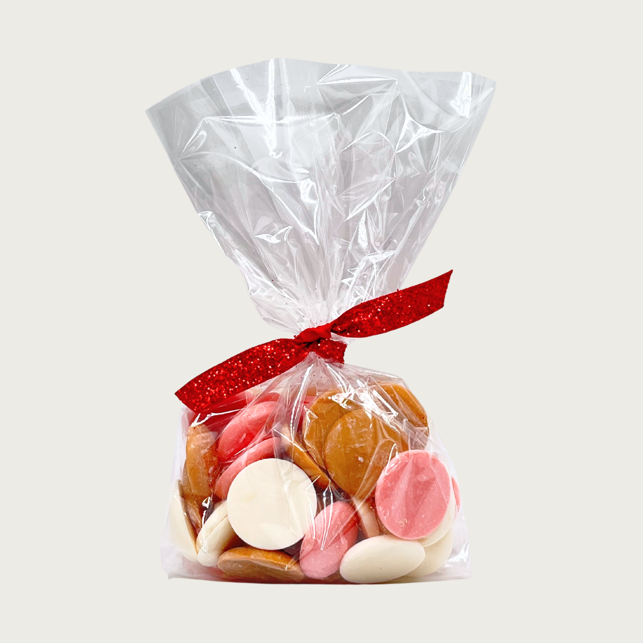 Clear cellophane bag tied with red ribbon of Wet Nose Guilty Pleasures NeaPAWlitan Flavor Dog Treats. Tan, cream, and pink disc-shaped treats are inside. 4 oz.