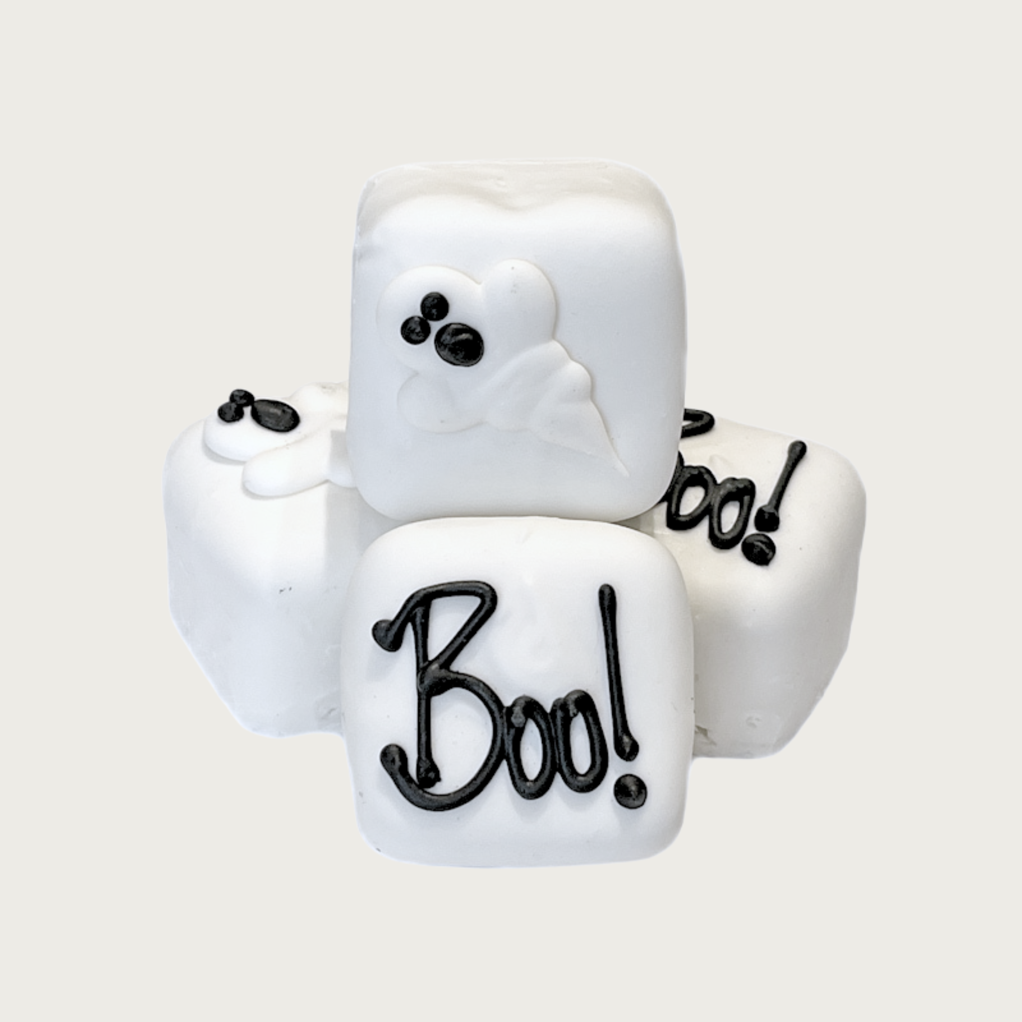 Four square shaped Bon Bon dog treats, stacked to show dimension. They are all white, 2 of them have "Boo!" written in black, the other 2 have a 3D ghost shape on top with black eyes & mouth.