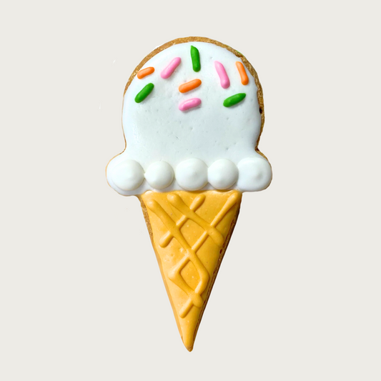 Decorative ice cream cone shaped dog cookie with white frosting and colorful sprinkles.