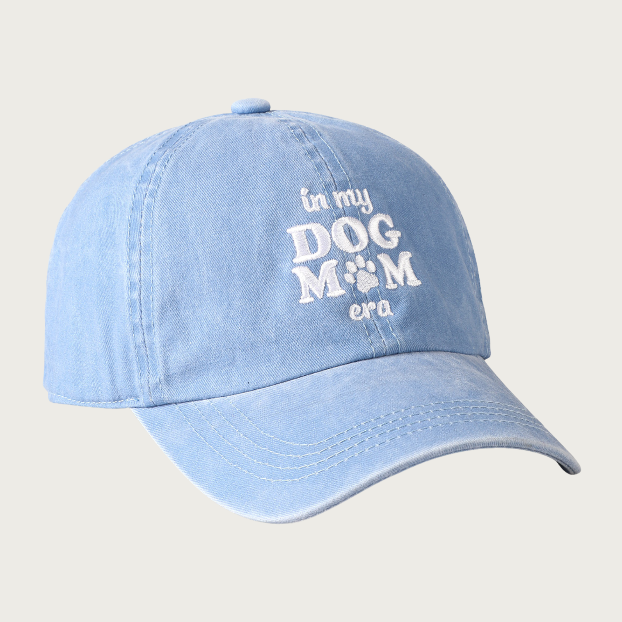 Light blue baseball cap with embroidered 'in my DOG MOM era' text in white. The "o" in mom is a paw print.