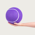 Load image into Gallery viewer, A large purple tennis ball being held in a person's hand to show size.
