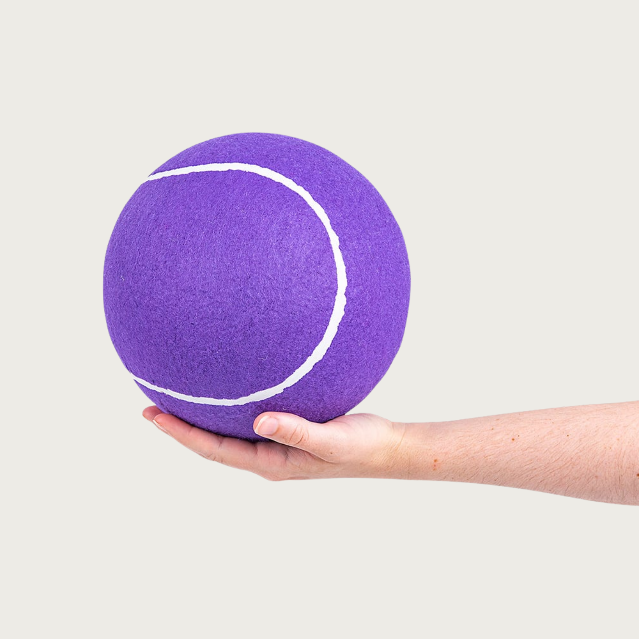 A large purple tennis ball being held in a person's hand to show size.