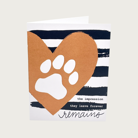 Pet loss sympathy card with a brown heart with white paw print on a black & white, wide rustic striped background. Text on bottom right reads, "the impression they leave forever remains"