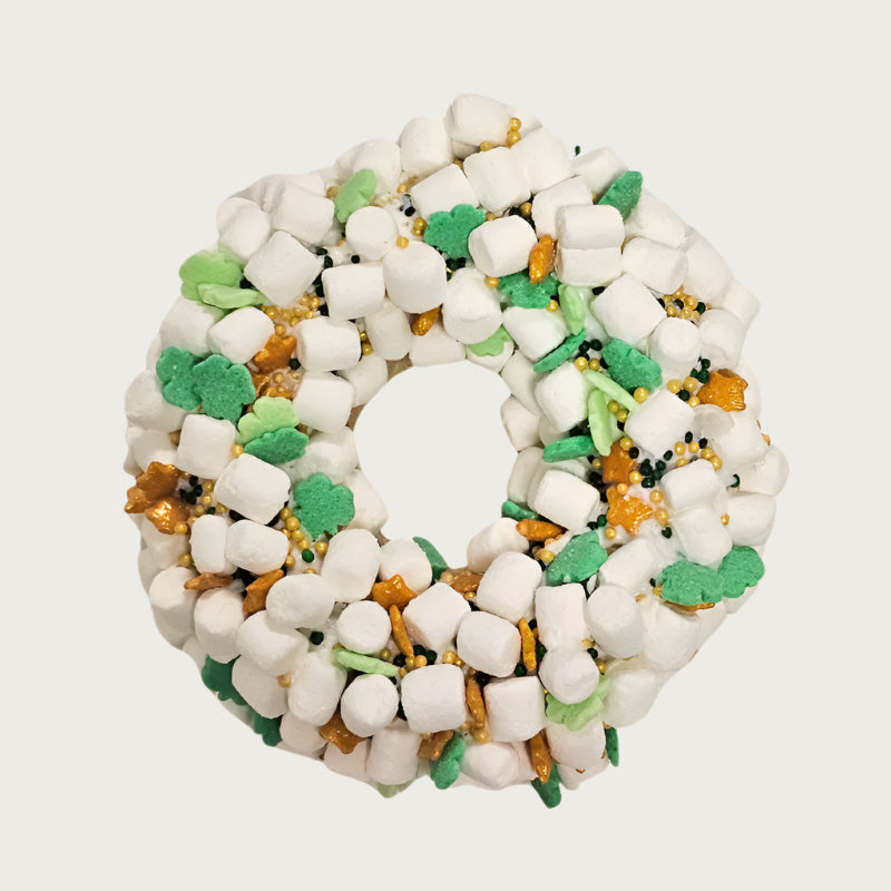 St. Patrick's Day themed, donut shaped dog cookie dipped in vanilla coating, and covered with tiny marshmallows, and accented with clover shaped decorettes, gold stars, and black & gold non-pareils.