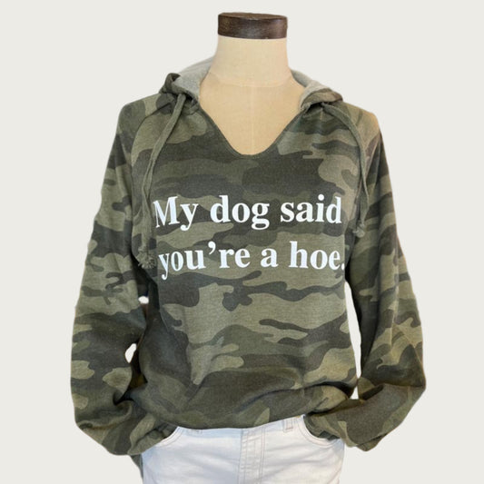 A camouflage hoodie in shades of olive green, with a slight v-neck. White text on chest reads "My dog said you're a hoe."