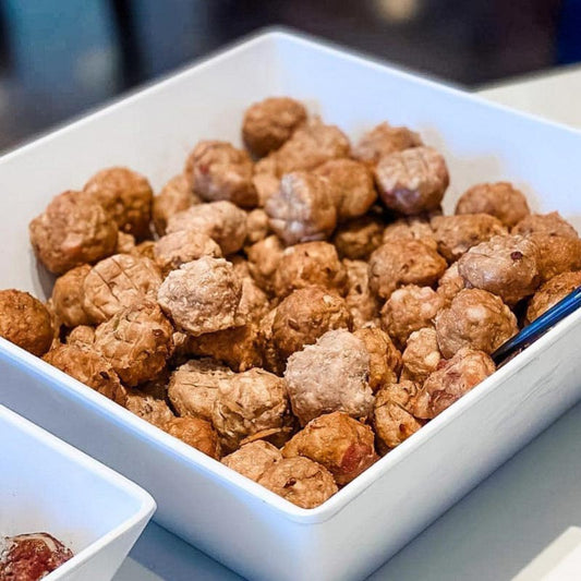 A white square bowl filled with freshly made meatballs, designed for pets.