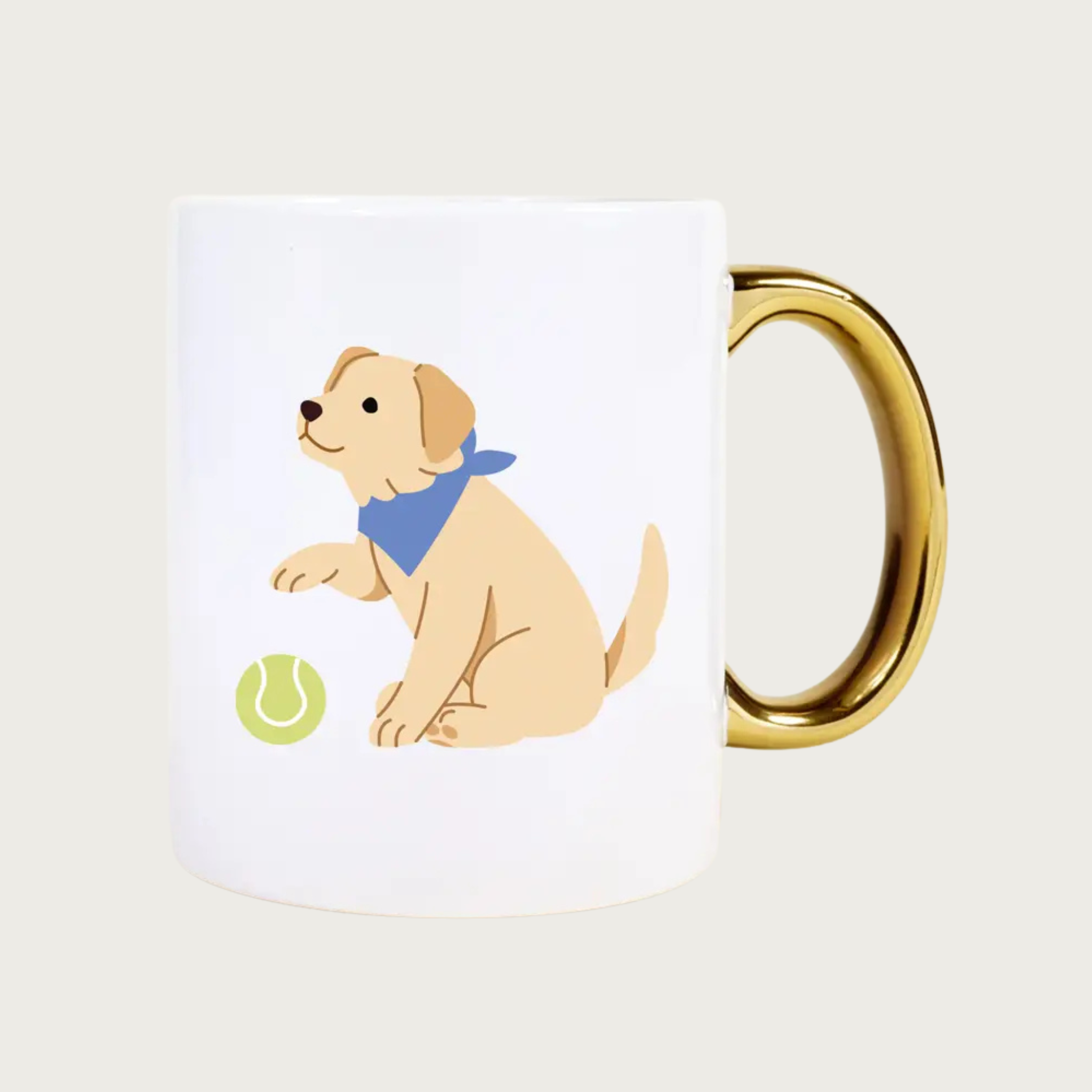 White ceramic mug with a gold handle, and dog illustration on the front, of a sitting golden retriever type dog wearing a blue bandana, with a green tennis ball under its paw.