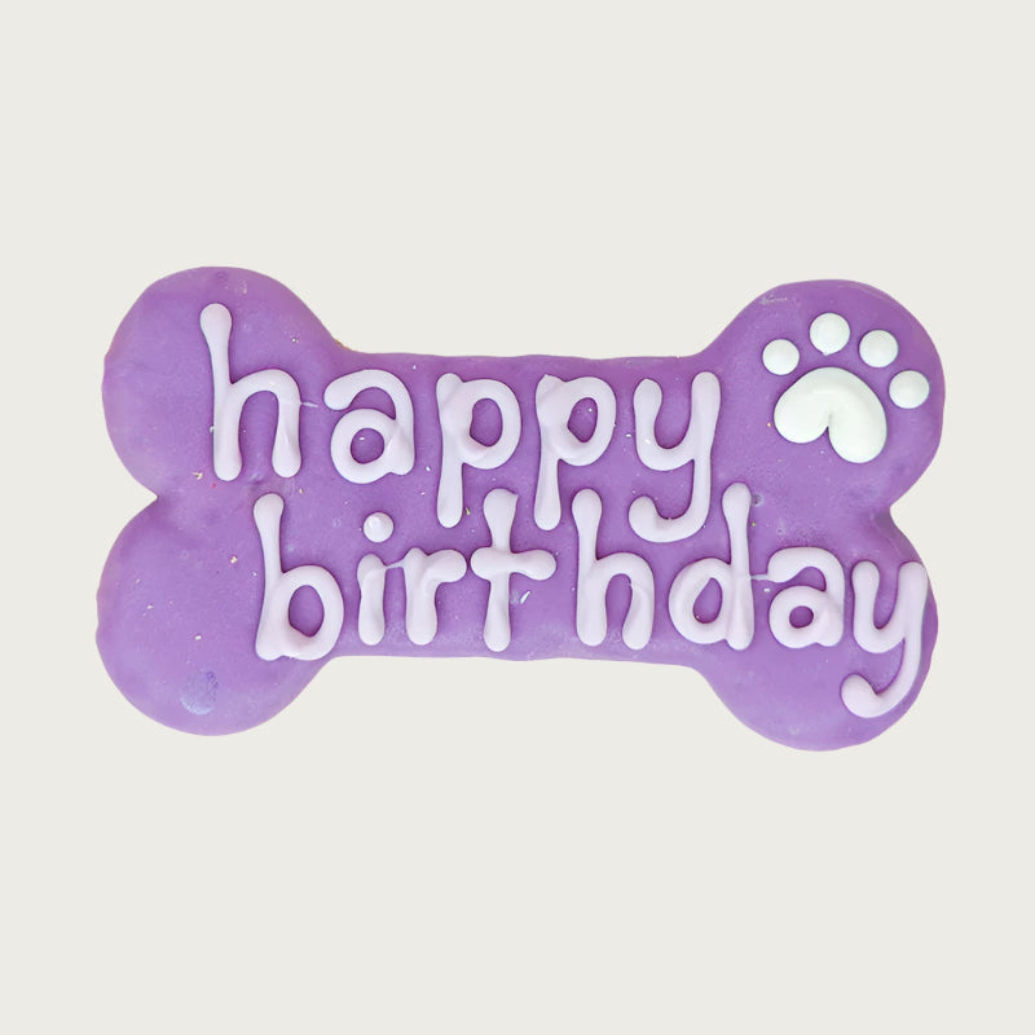 Purple bone-shaped dog cookie with 'happy birthday' text in white, with white paw print accent.