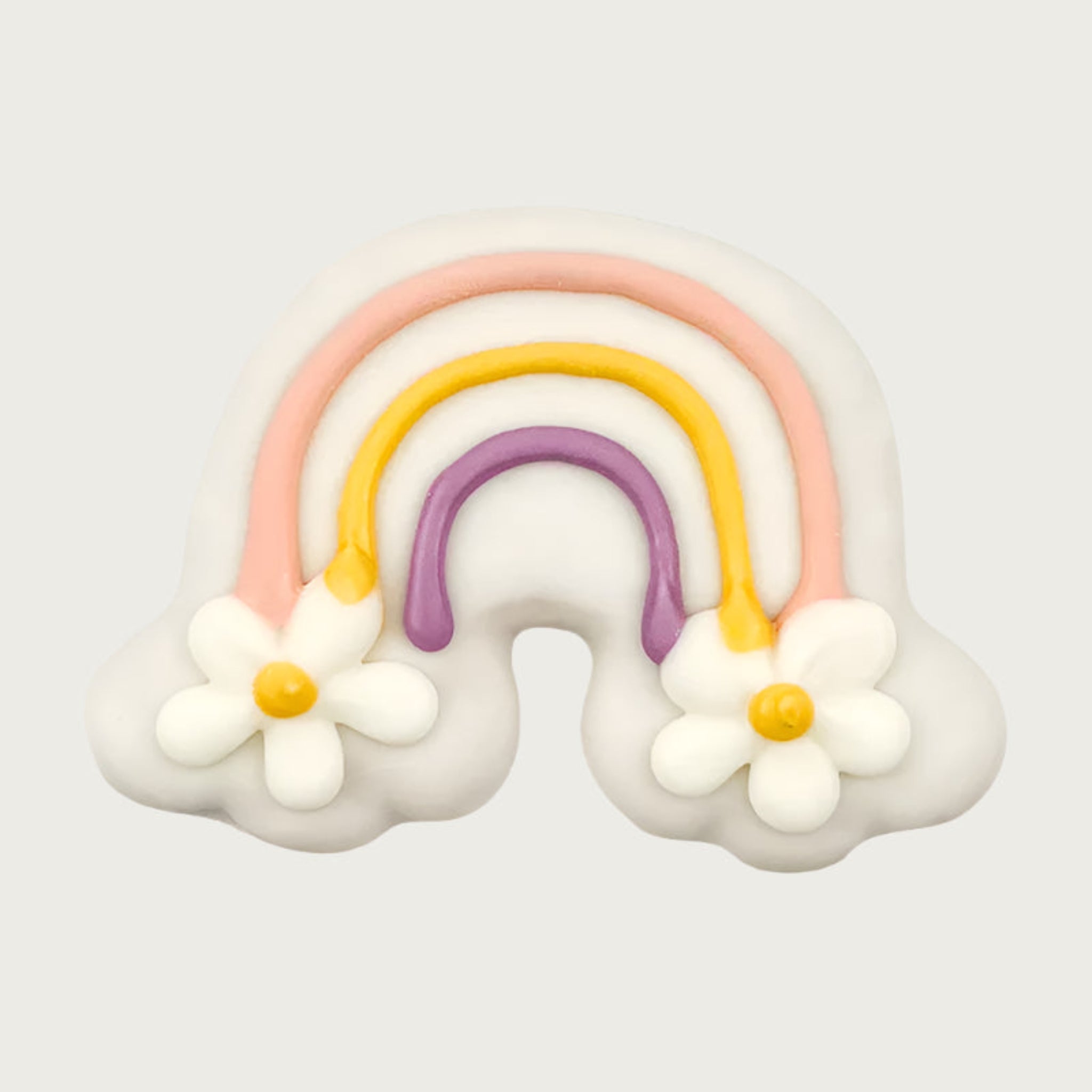 Decorative rainbow dog cookie, with pink, yellow and purple colors. At each end of the rainbow, there are large daisies instead of clouds.