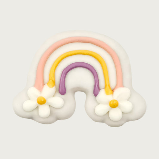 Decorative rainbow dog cookie, with pink, yellow and purple colors. At each end of the rainbow, there are large daisies instead of clouds.