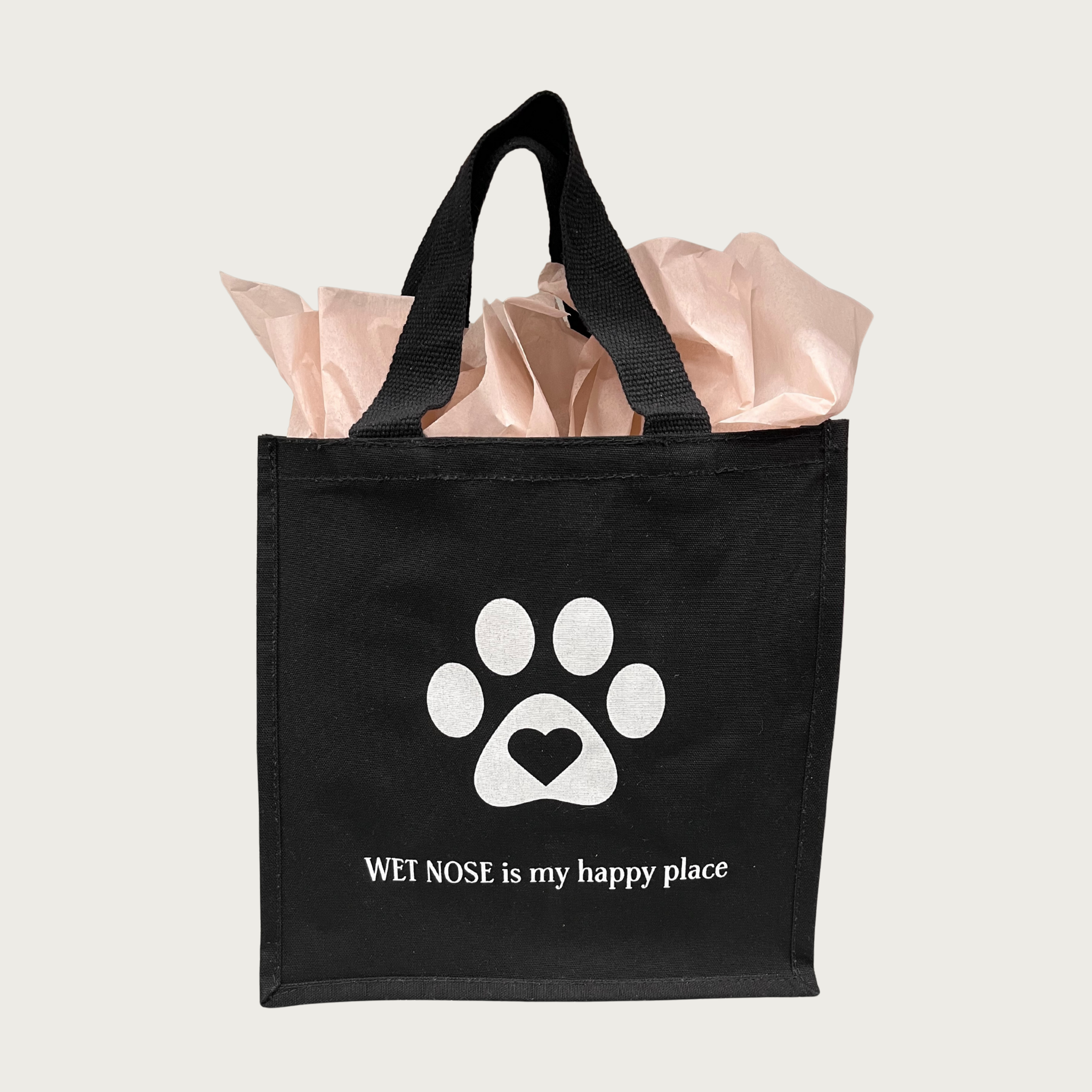 Black tote bag with white paw print with heart in center. Beneath it reads "Wet Nose is my happy place" in white text.