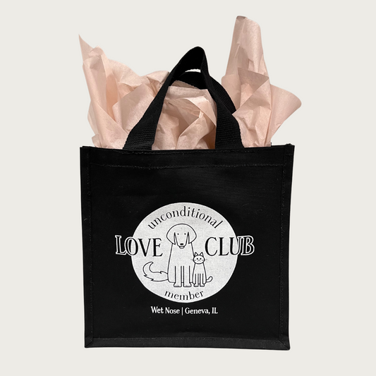 Black tote bag with round, white logo in center that reads 'Unconditional Love Club Member', with cute dog & cat line drawings. Underneath the logo reads: Wet Nose, Geneva, IL in white text.