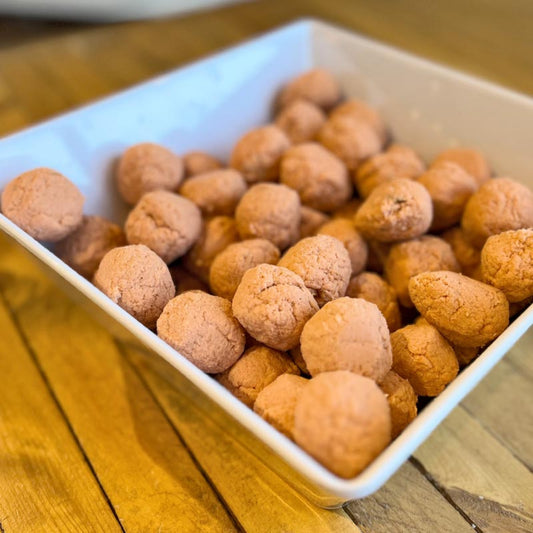 A white square bowl filled with homemade salmon meatballs on a wooden table.