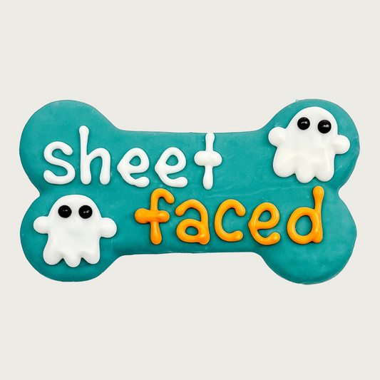 Teal bone-shaped dog cookie with white ghosts and 'sheet faced' text in white and orange.