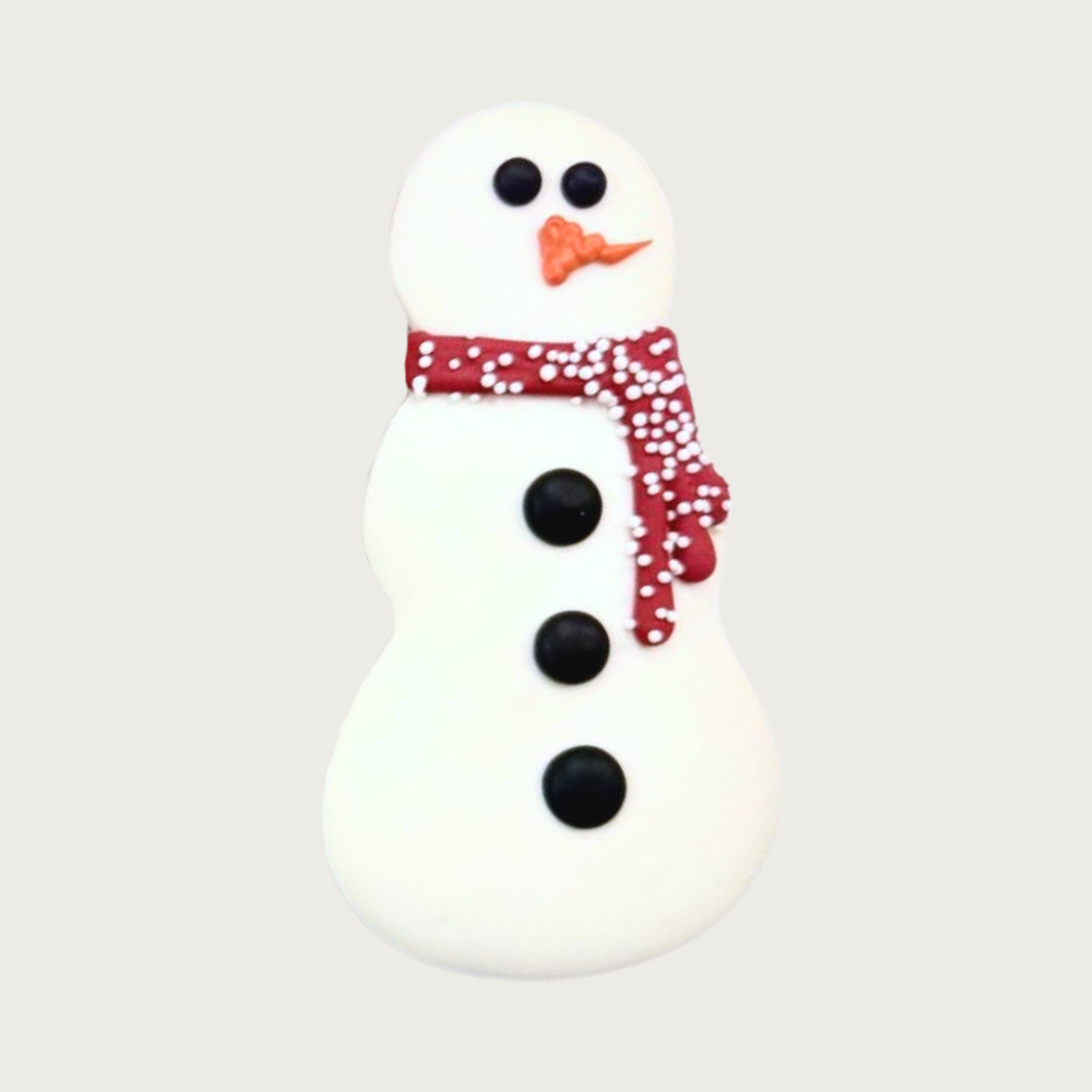 Decorated dog cookie in the shape of a snowman, with black eyes & buttons, orange carrot-shaped nose, and red scarf with white nonpareils.