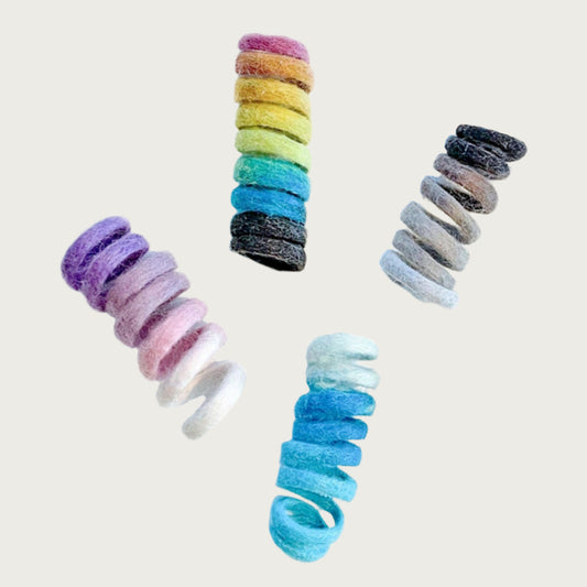 Group of 4 spring-shaped, wool cat toys, in different colors. Rainbow, pink ombre, teal blue ombre, and natural ombre (shades of brown).