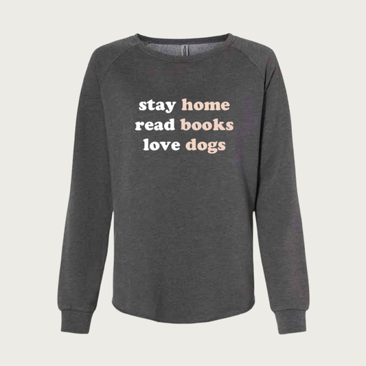Charcoal gray, crewneck sweatshirt with lowercase text on front that reads on 3 lines, "stay home, read books, love dogs". The words "stay, read, love" are in white. The words "home, books, dogs" are in blush pink.