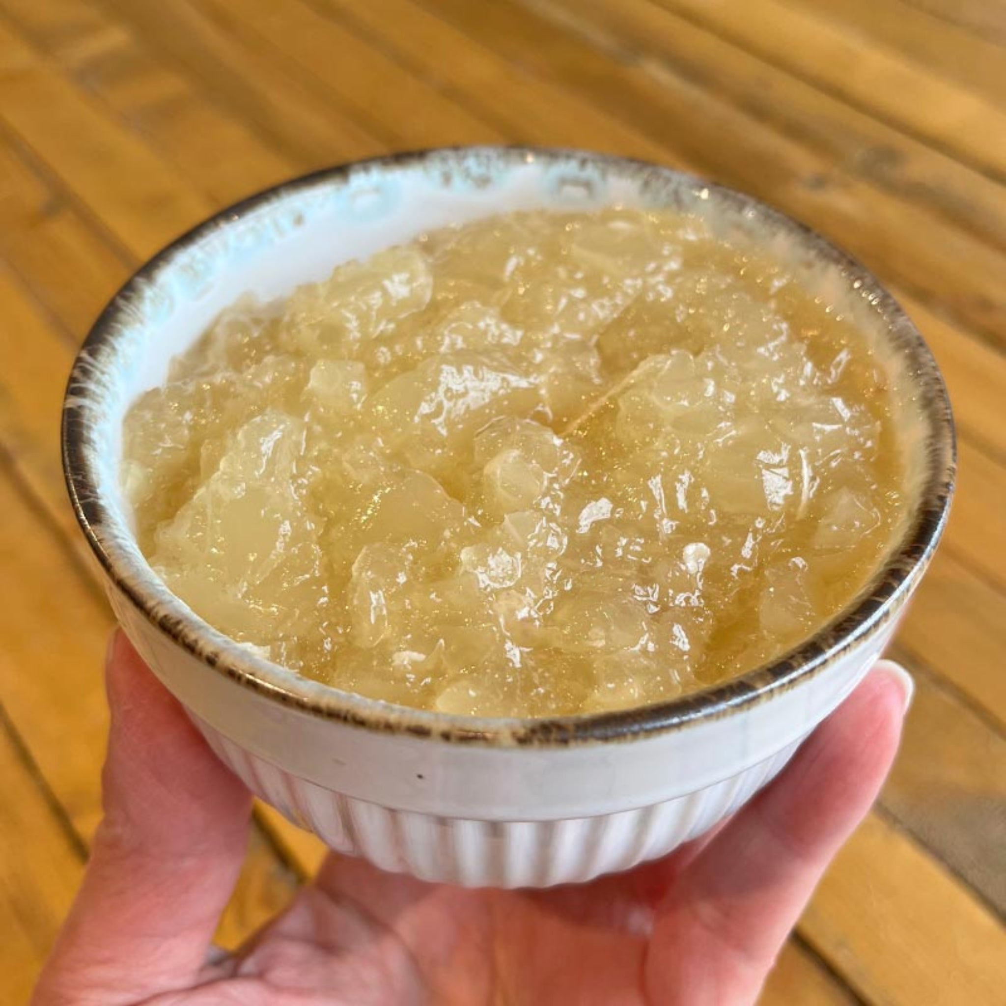 A bowl of homemade Turkey Bone Broth for pets, that's light golden yellow in color and gelatinous in texture.
