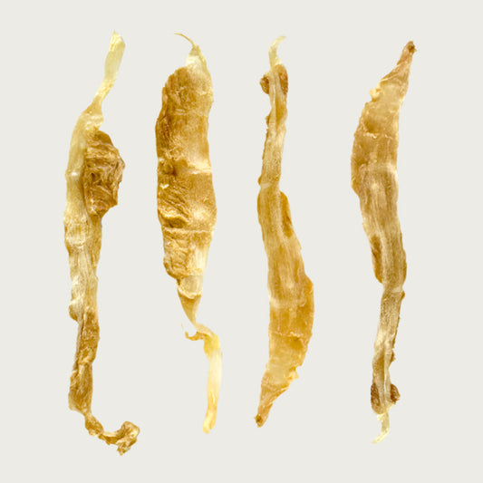 Close-up photo of four Wet Nose Turkey Twists dog treats, side by side. They are tan, about 7"-10" long, thin, narrow, with an uneven shape.
