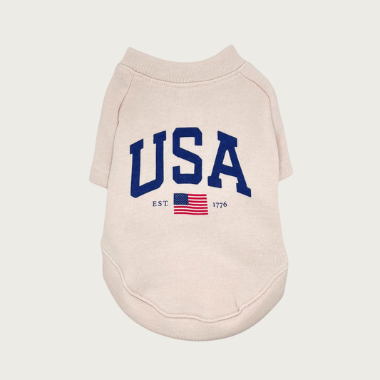 Cream colored pet sweatshirt with large "USA" navy blue text in center, with a smaller USA flag underneath with "EST." text on left side and "1776" on the right side.