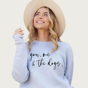 Blonde model wearing a tan hat, wearing this sweatshirt. Color is pale, light blue with black script text that reads "you, me & the dogs".