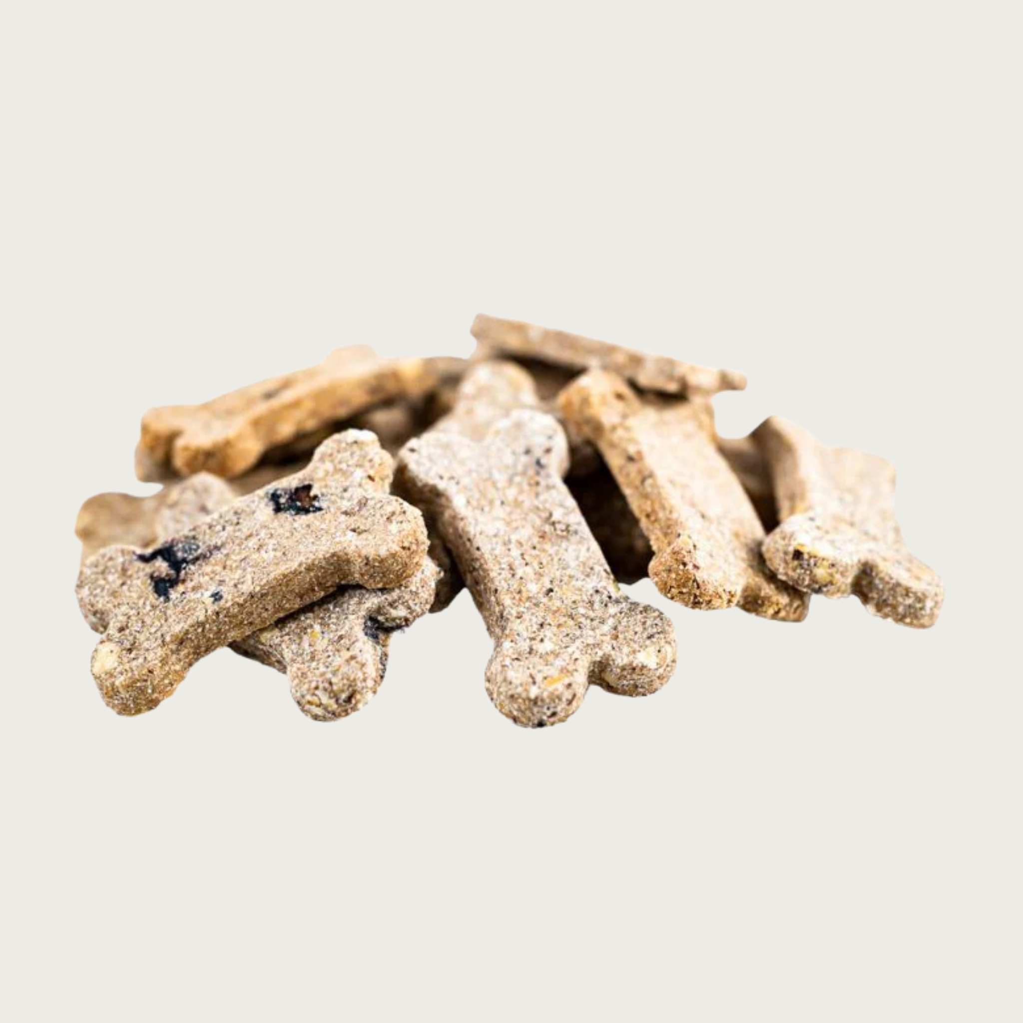 Closeup of a small pile of Berry Boost Bones dog treats. They are dog bone shaped, beige in color with visible berry pieces inside, with a grainy texture.