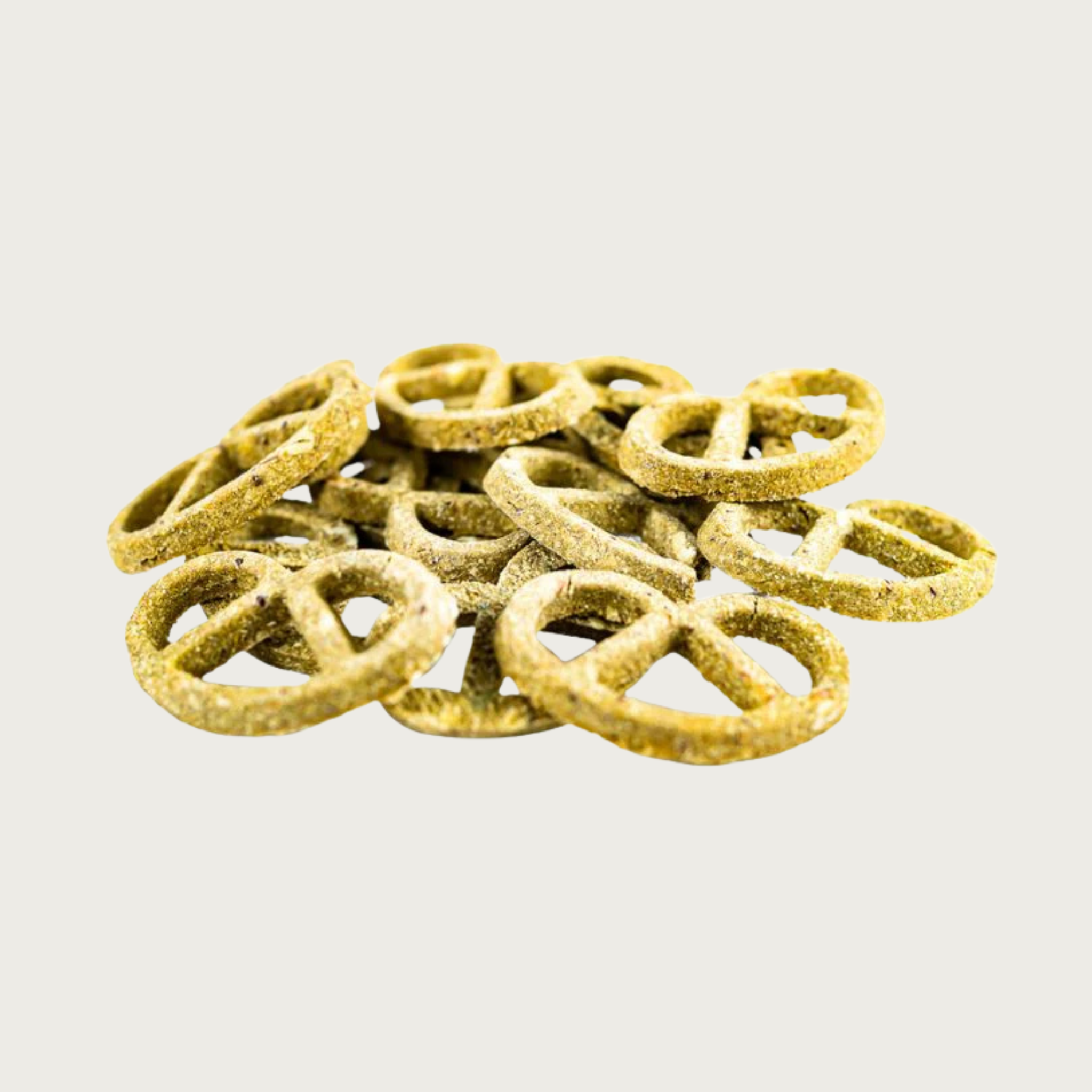 Closeup of a small pile of Greens & Cheddar Pretzels dog treats. They are thin and light greenish brown in color, with a grainy texture.
