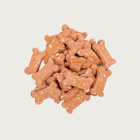 Closeup of a small pile of Strawberry Shortcake Bones dog treats. They are dog bone shaped, pinkish in color, with a grainy texture.