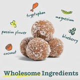 Close-up image of four Calming Pupsicle Pops in center (tan, smooth balls coated in coconut), with illustrations of the key ingredients; coconut, passion flower, tryptophan, magnesium, and blueberry. Text on bottom reads "Wholesome Ingredients". 