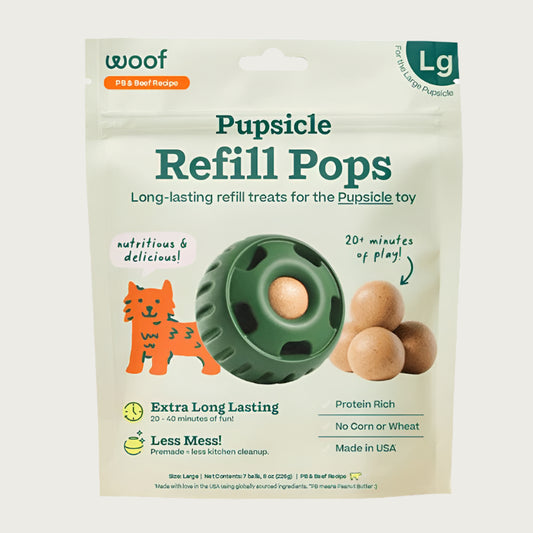 7 ct bag of large Woof Pupsicle Refill Pops, long-lasting refill treats for the Pupsicle toy. Extra long lasting, less mess. Image of green Pupsicle toy is in center, with refill pop inside, with sample pops clustered to the right. They are round, peanut butter colored, smooth balls.