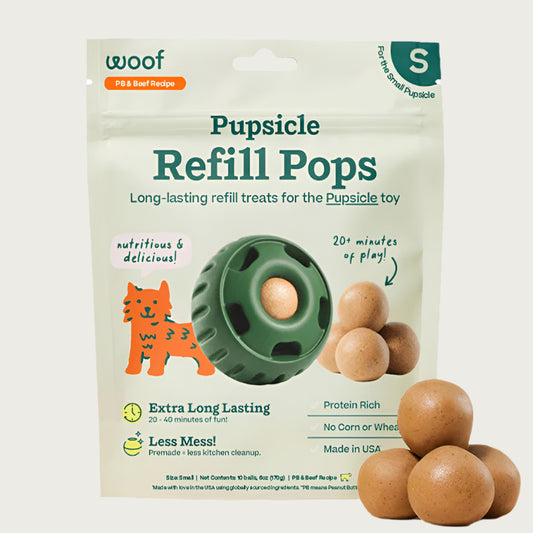 10 ct bag of small Woof Pupsicle Refill Pops, long-lasting refill treats for the Pupsicle toy. Extra long lasting, less mess. Image of green Pupsicle toy is in center, with refill pop inside, with sample pops clustered to the right. They are round, peanut butter colored, smooth balls.