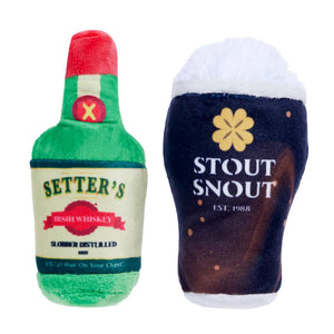 Two small plush "parody" dog toys side by side. The toy on the left looks like a green whiskey bottle, and its label reads "Setter's Irish Whiskey - Slobber Distilled". The toy on the right looks like a glass of dark brown stout beer with foam on top ,with a gold clover above the centered text that reads "Stout Snout Est. 1988".