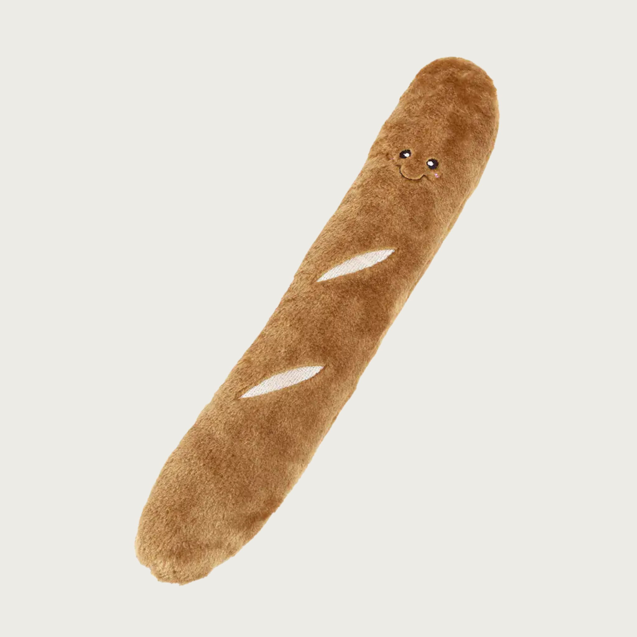 A dog toy shaped like a baguette, with soft brown plush and embroidered white slashes and a small embroidered smiling face.