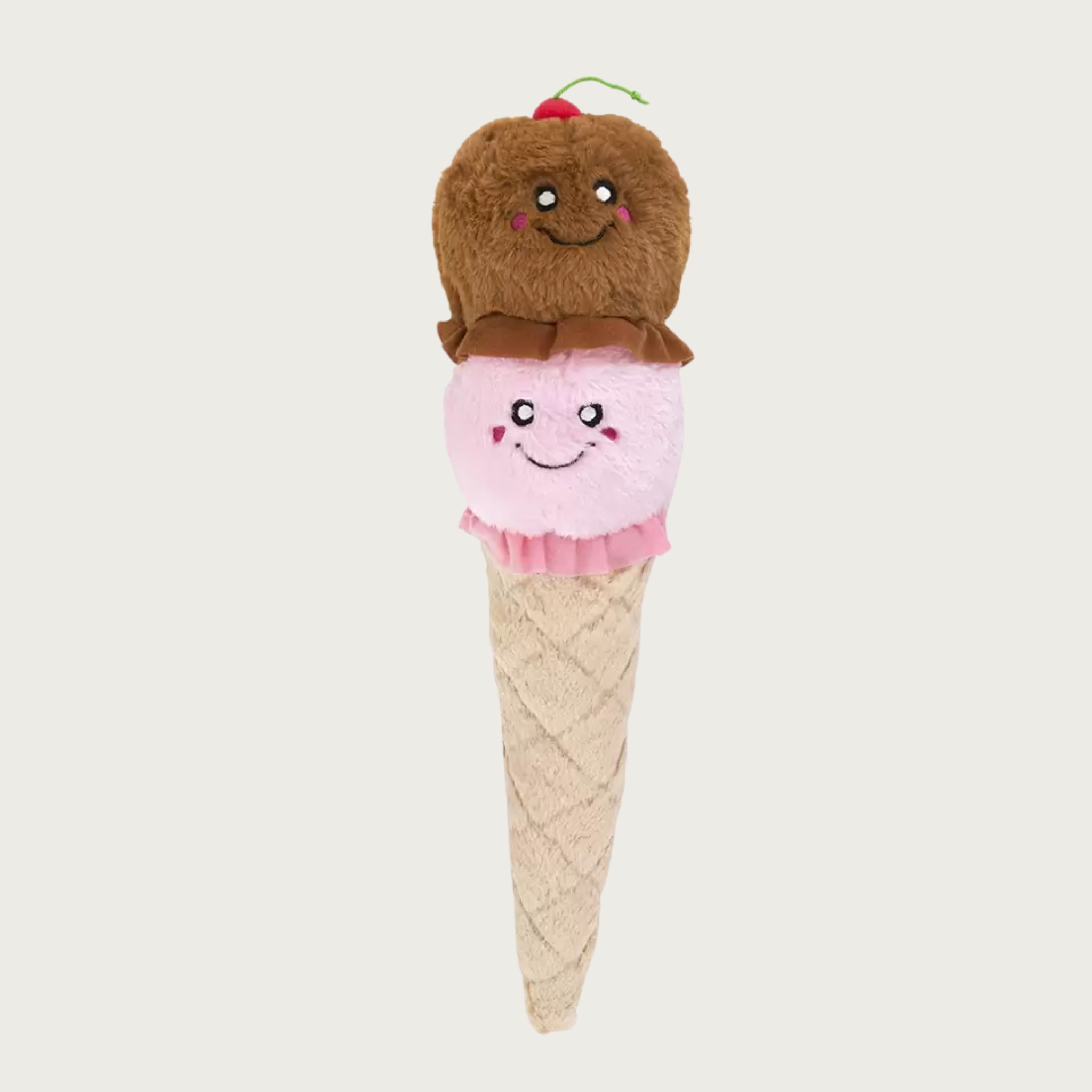A plush dog toy designed to look like a 2-scoop ice cream cone. Bottom scoop is pale pink and top scoop is brown with a cherry on top. Both scoops have cute embroidered smiley faces. They are on top of a light beige cone base with lattice details.