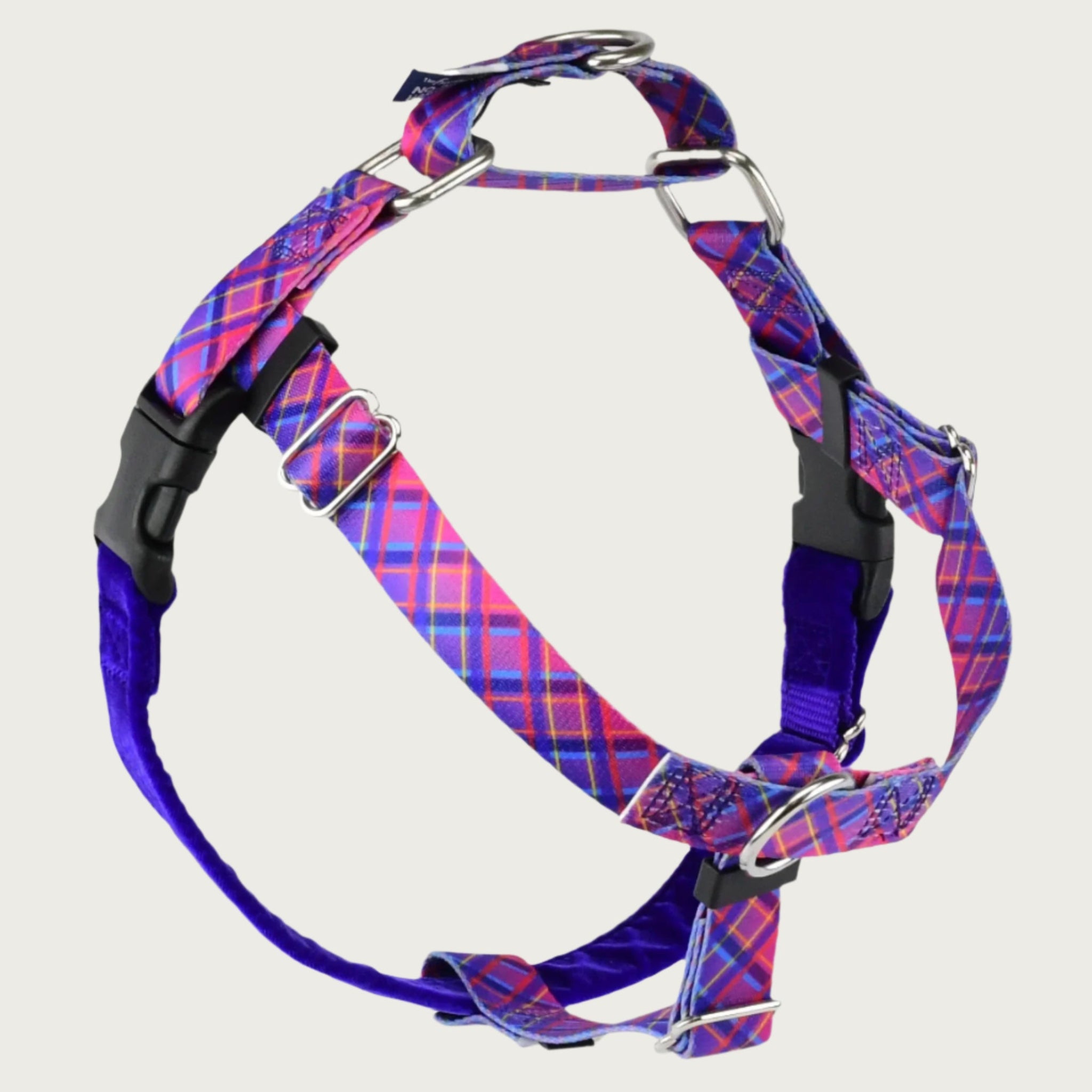 Dog harness with bright pink & purple plaid straps on the front and sides; loop on dog's back is same color & pattern. Chest strap is bright purple velvet. There are 2 black plastic clips, which fasten behind each front leg. 