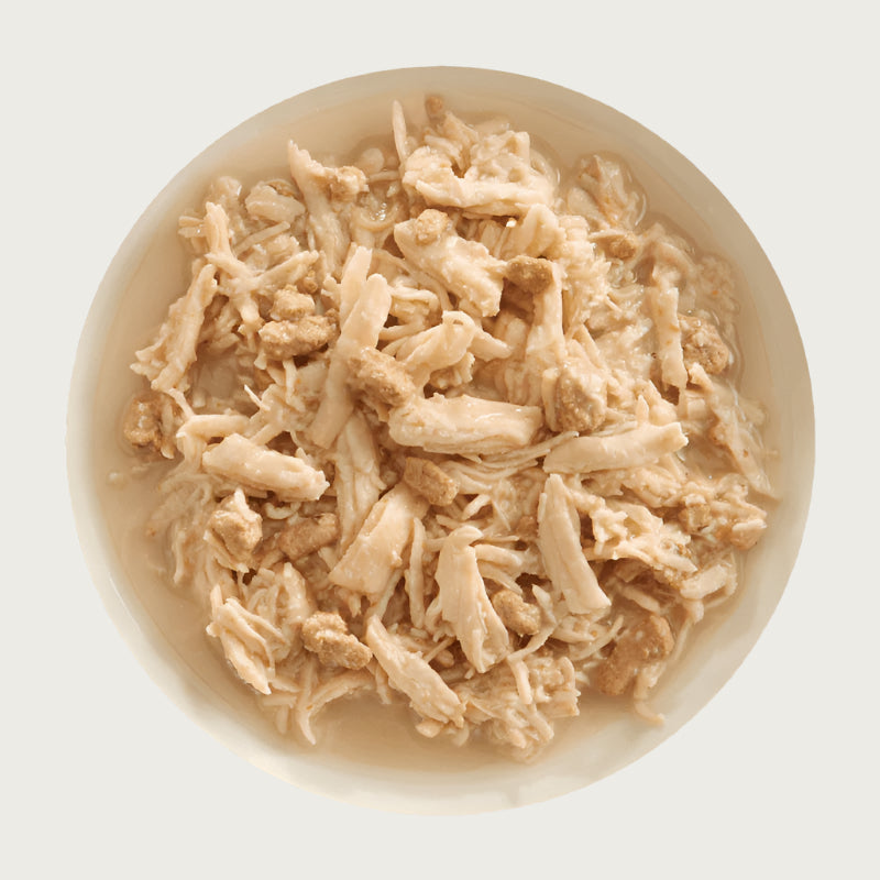 A bowl of Aujou by RAWZ Chicken Breast & Chicken Liver recipe, showing large chunks of chicken with smaller shreds and small pieces of chicken liver.