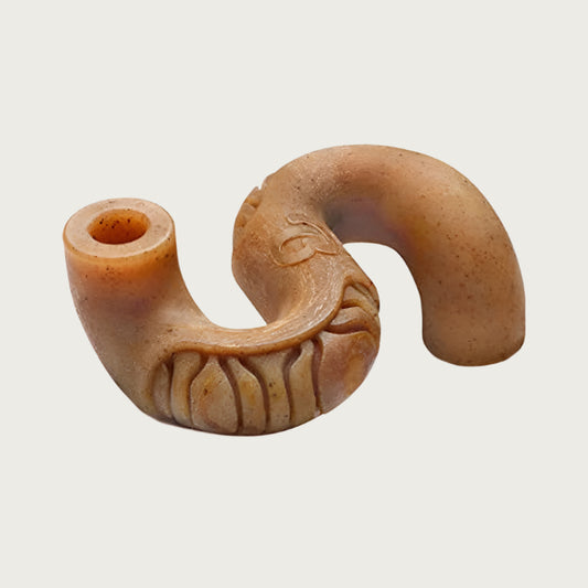 Brown, S-shaped hard chew toy. One end curves down, and the other curves up. There are small openings at each end, and the body has shallow ridges on it.