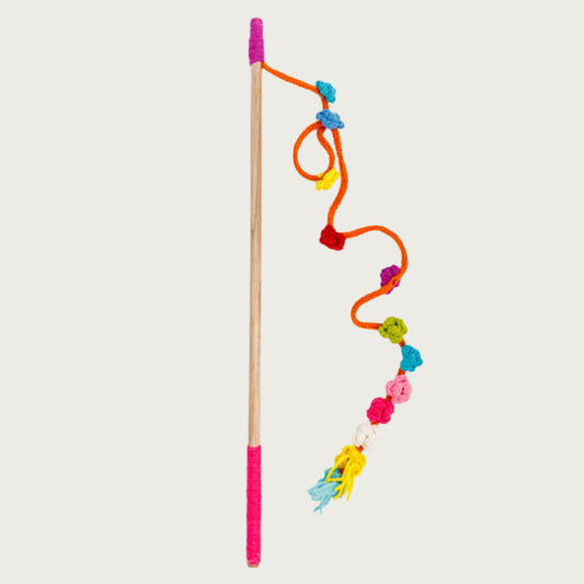 Wooden pole with yarn covered ends, with a long string attached at one end. The thick string has multiple crocheted flowers attached in assorted colors, and unevenly spaced.
