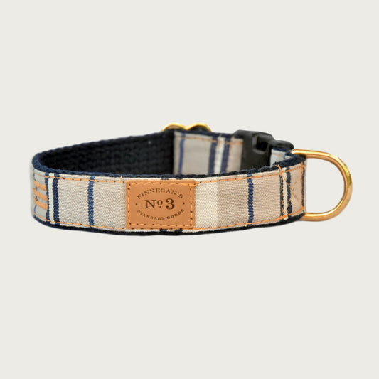 Dog collar with simple vertical striped pattern. Base colors are blocks of cream and beige, with narrow & widely spaced navy blue and white stripes.