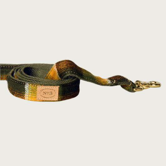 Dog leash with a wide-set plaid pattern, in earthy shades of olive green, black, and mustard yellow.