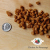 A close-up image of a handful of dry Chicken au Frommage kibble pieces, next to a dime for size comparison. About 5-6 of the pieces would fit into the area of the dime. They are very small and have a rounded triangle shape.