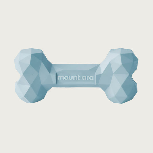 A light blue, heavy rubber dog bone toy with geometric texture.