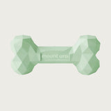 A pale green, heavy rubber dog bone toy with geometric texture.