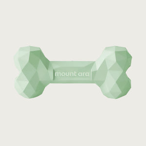 A pale green, heavy rubber dog bone toy with geometric texture.