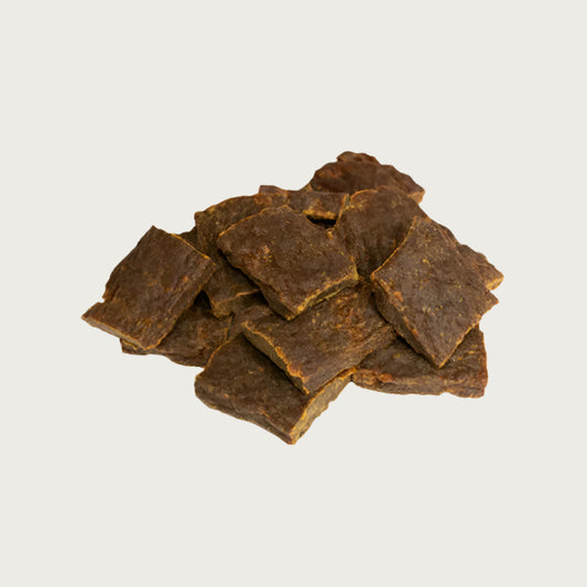 A close-up photo of a small handful of the Open Farm Beef dog treat. They are rectangular brown pieces that look like jerky, about 1"-2" long and 1/8" thick.
