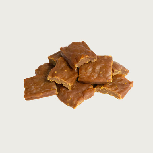 A close-up photo of a small handful of the Open Farm Chicken dog treat. They are rectangular brown pieces that look like jerky, about 1"-2" long and 1/8" thick.