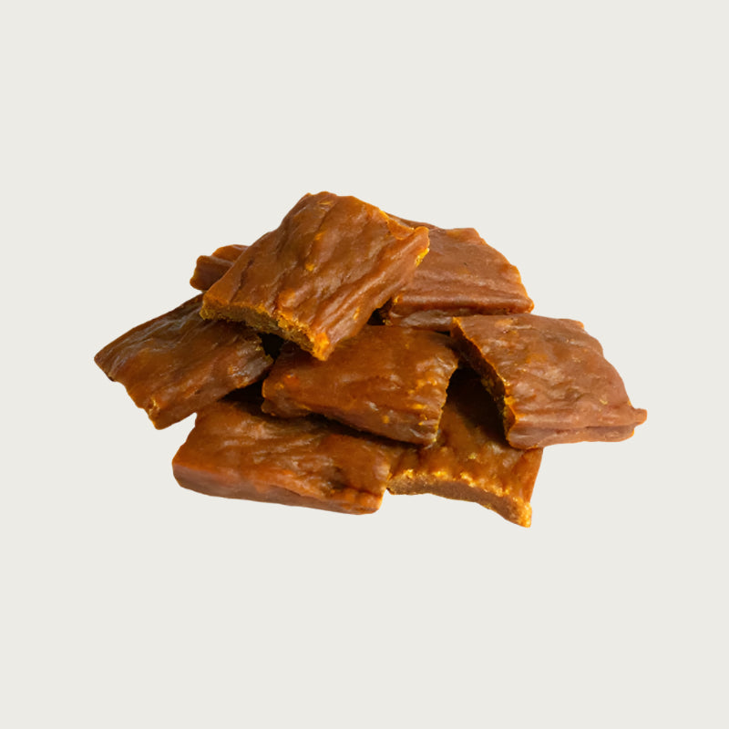 A close-up photo of a small handful of the Open Farm Turkey dog treat. They are rectangular brown pieces that look like jerky, about 1"-2" long and 1/8" thick.