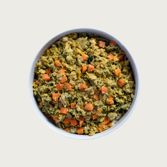 A close-up bowl of Open Farm's Gently Cooked recipe, showing a tan colored softly minced wet food mixed with green vegetables and diced carrots.