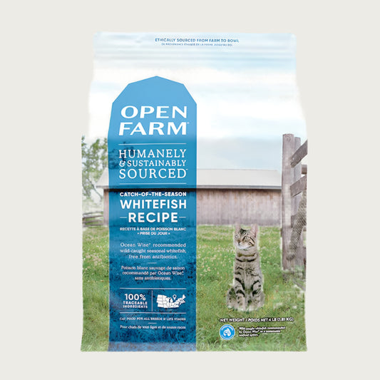 A bag of Open Farm Grain Free Whitefish Recipe cat food. Humanely and sustainably sourced. A photo of a tabby cat standing in a field on a farm covers the bag, with a blue bar behind the white text to highlight it.